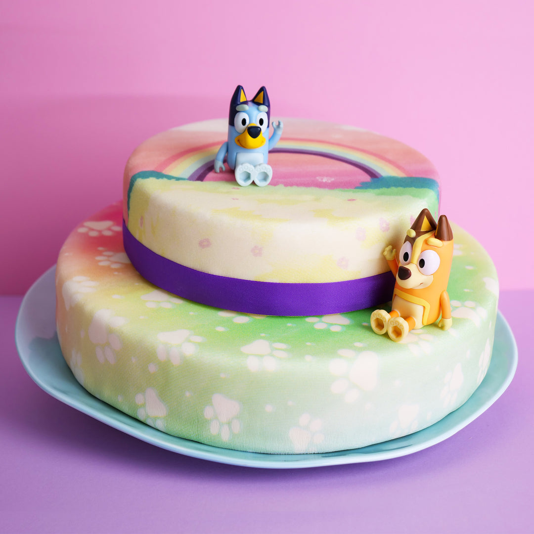 Bluey®-Figur auf 2-stöckiger Regenbogen-Torte