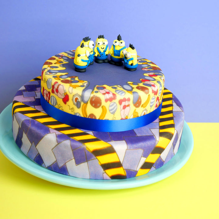 Minions® auf zweistöckiger schurkischer Muster-Torte
